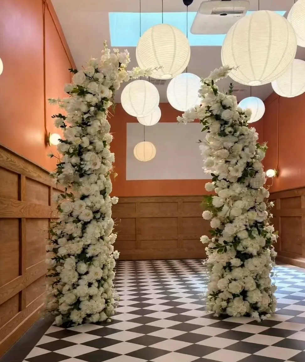 White faux floral arches set up in a warm reception room