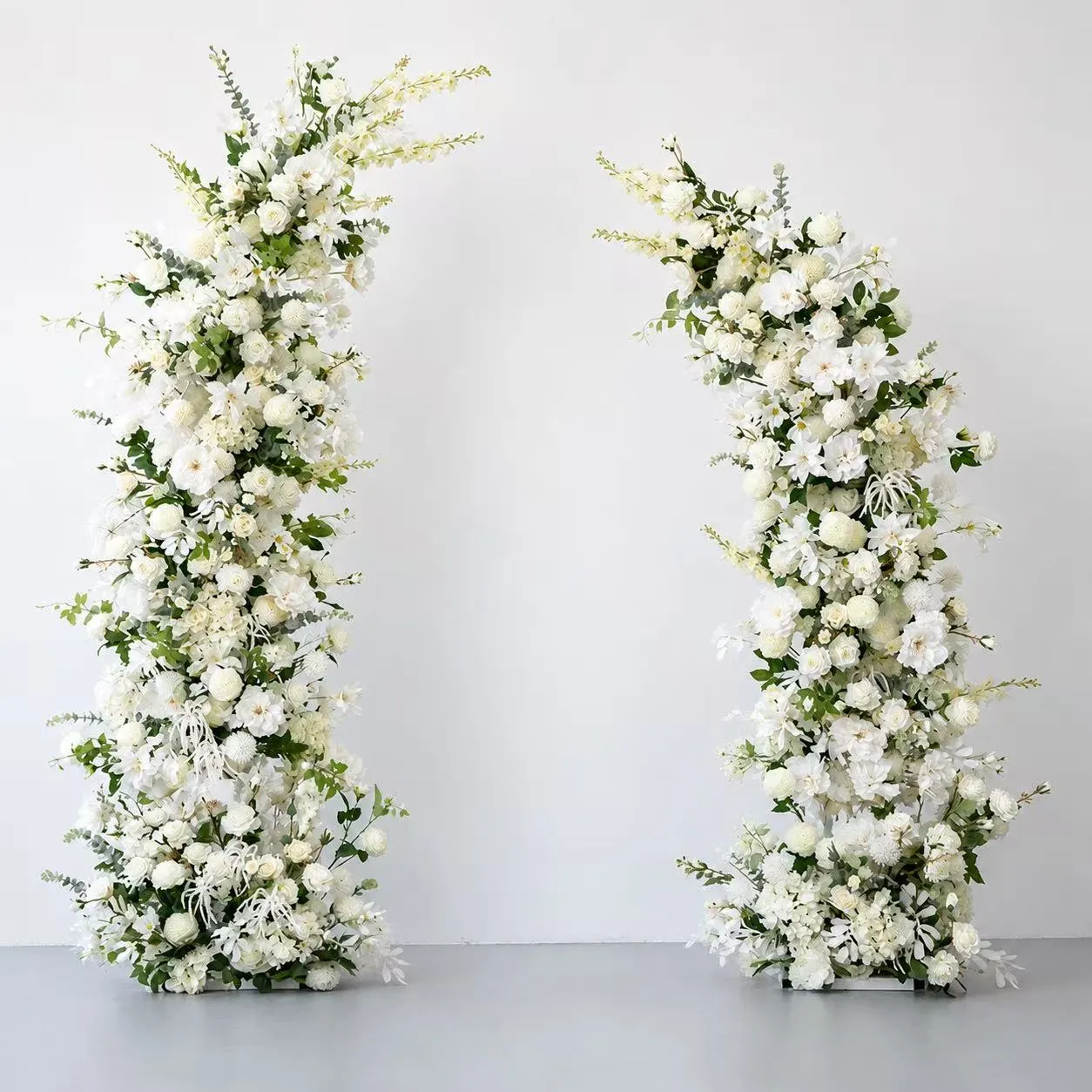 Pair of white faux floral arches in a studio